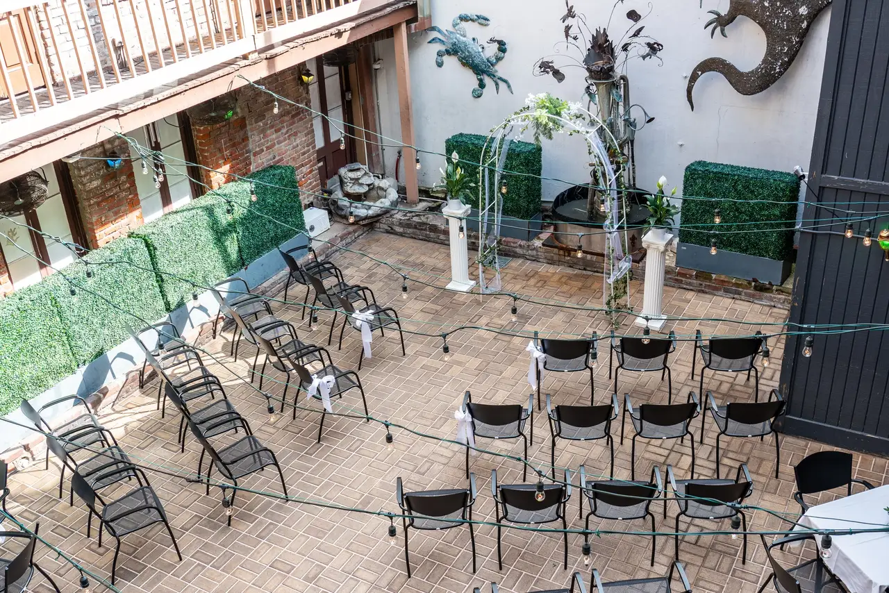 Looking down into the courtyard from the balcony: chairs, string lights and green hedges