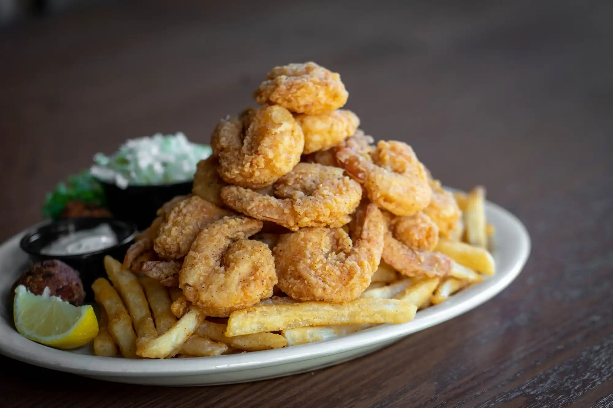 A fried shrimp platter with fries, coleslaw and lemon