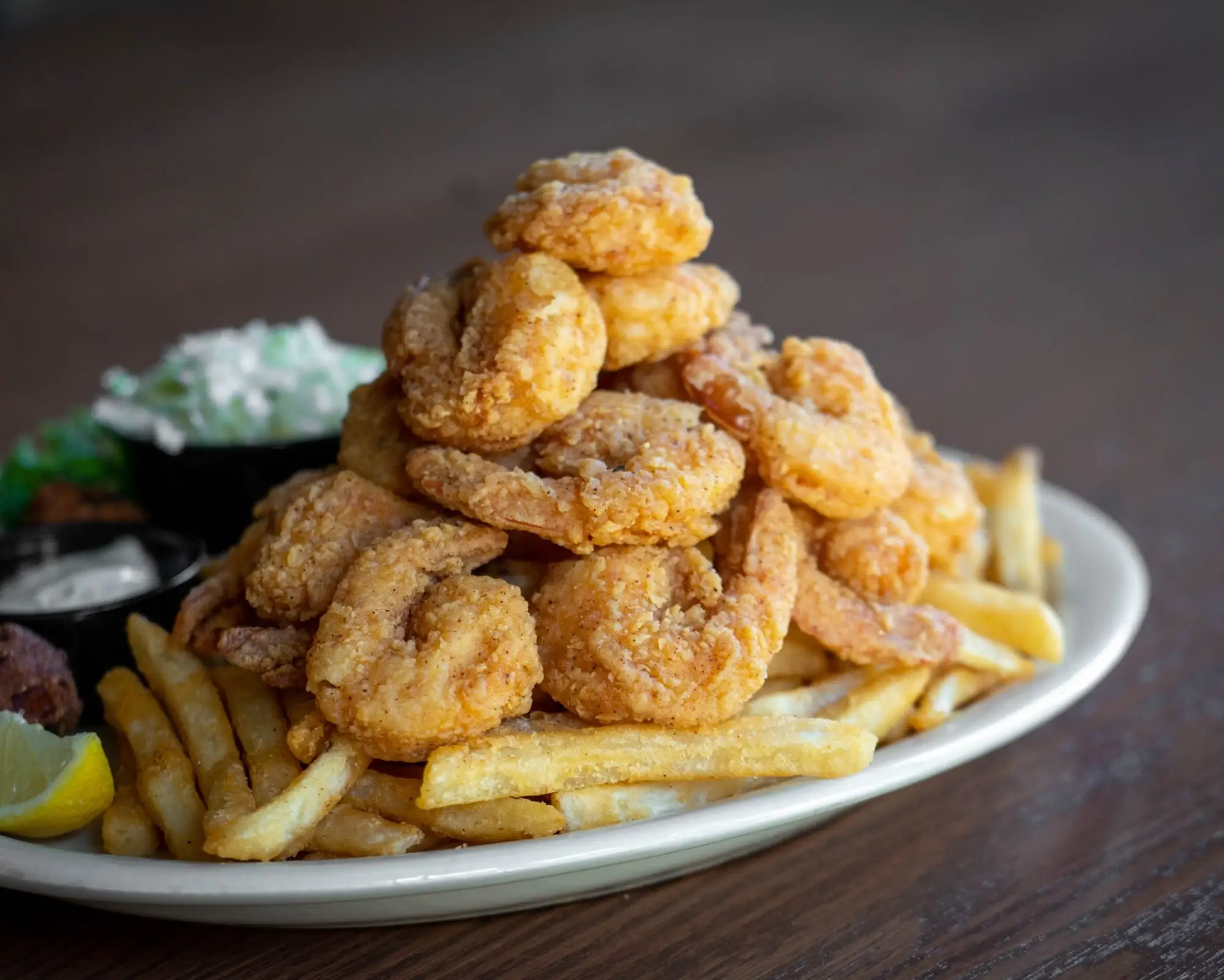A fried shrimp platter with fries, coleslaw and lemon