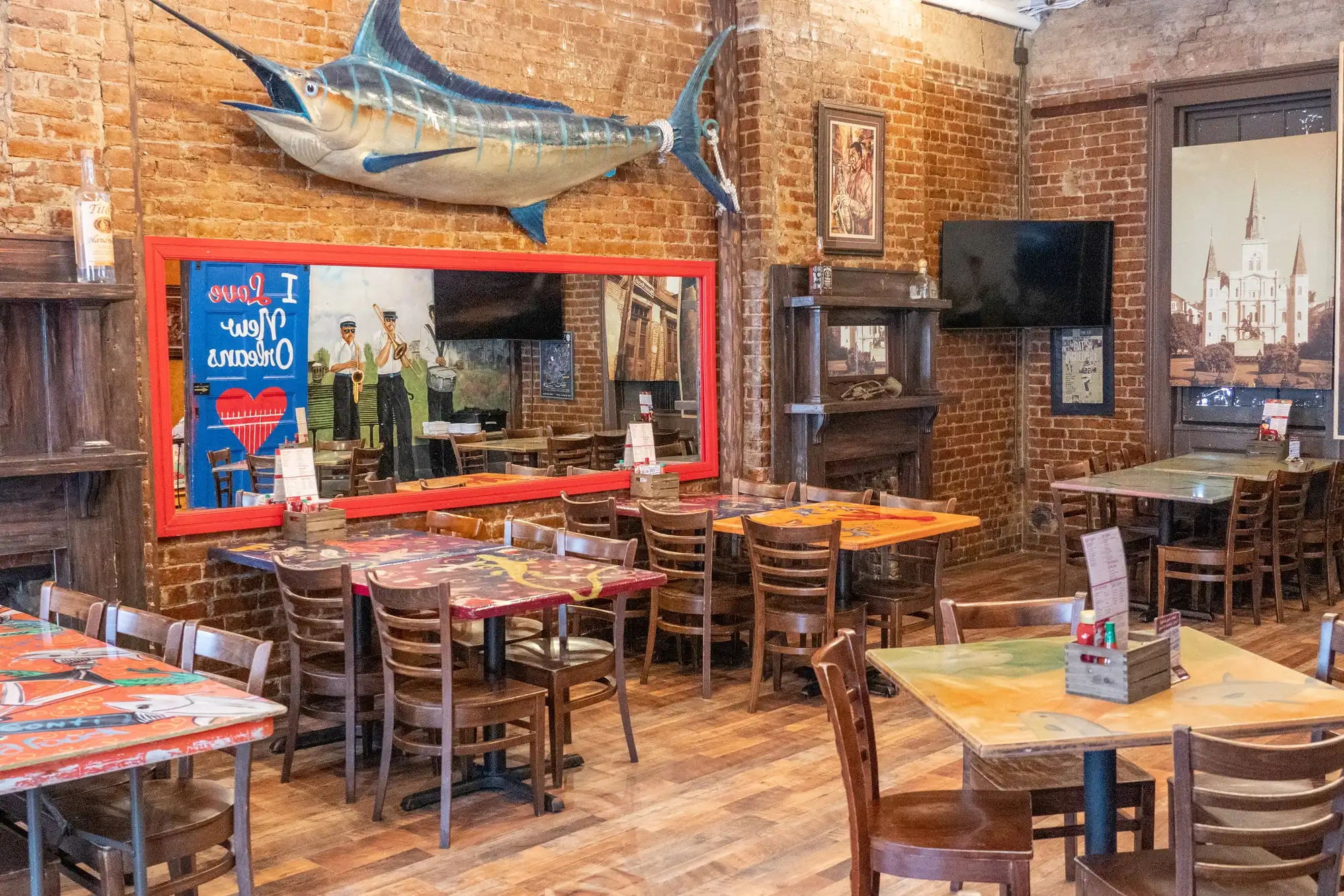 La Bohème Room: a mounted marlin over a red-framed mirror, painted tables and exposed brick
