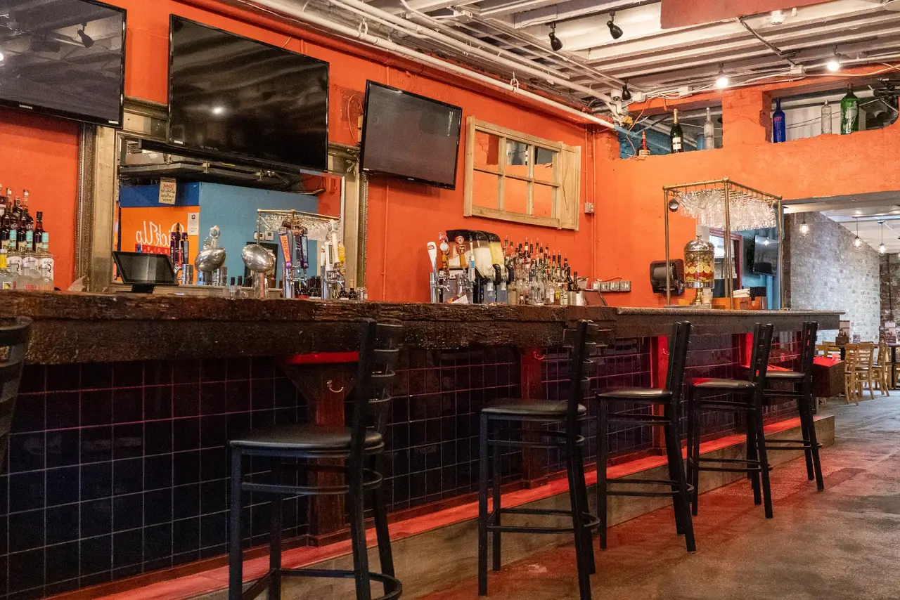 The bar at Oceana Grill: a long wooden counter and stools beneath a glowing orange wall