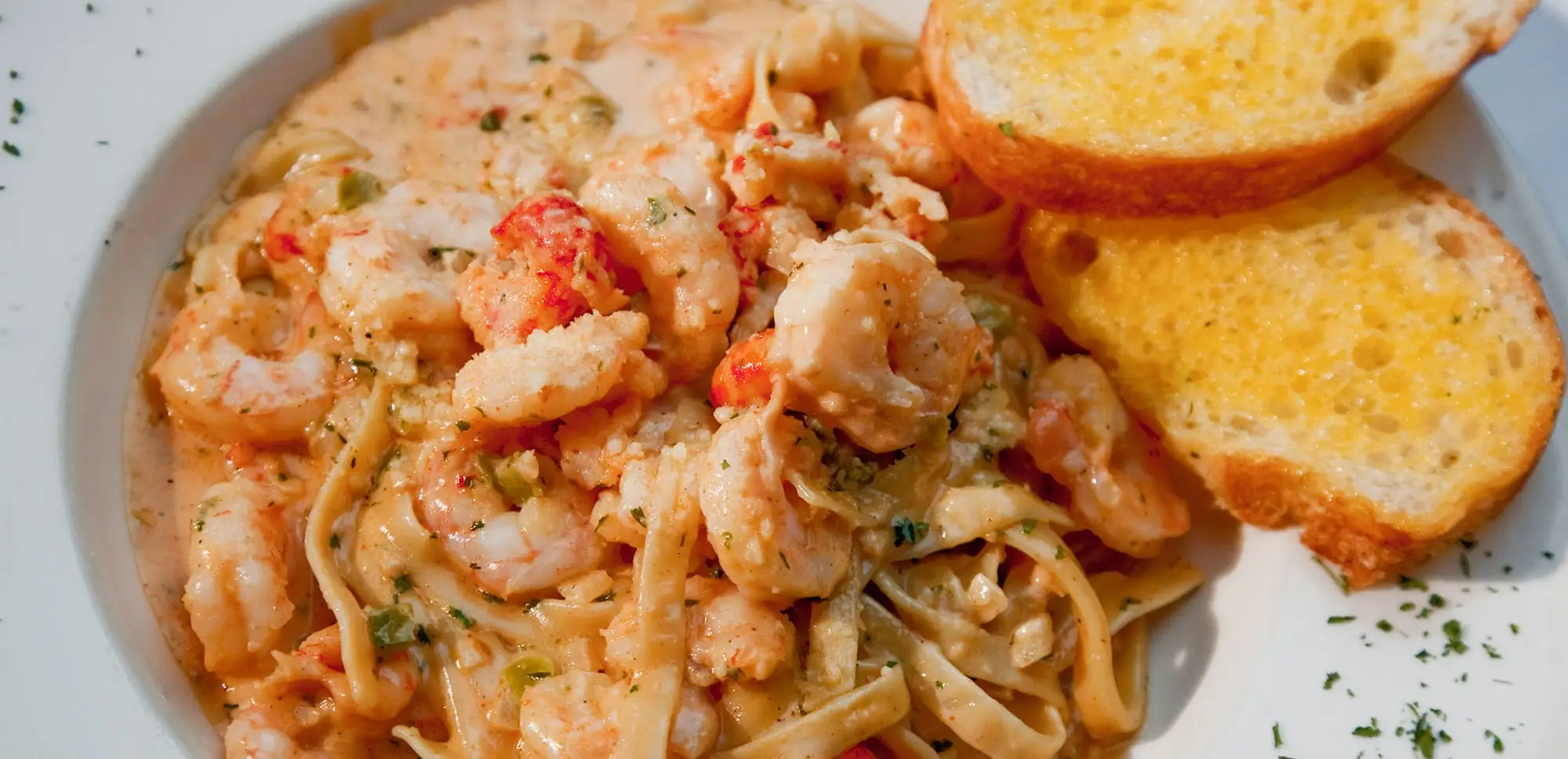 Mardi Gras pasta with Gulf shrimp and crawfish tails in a creamy Alfredo, with garlic bread