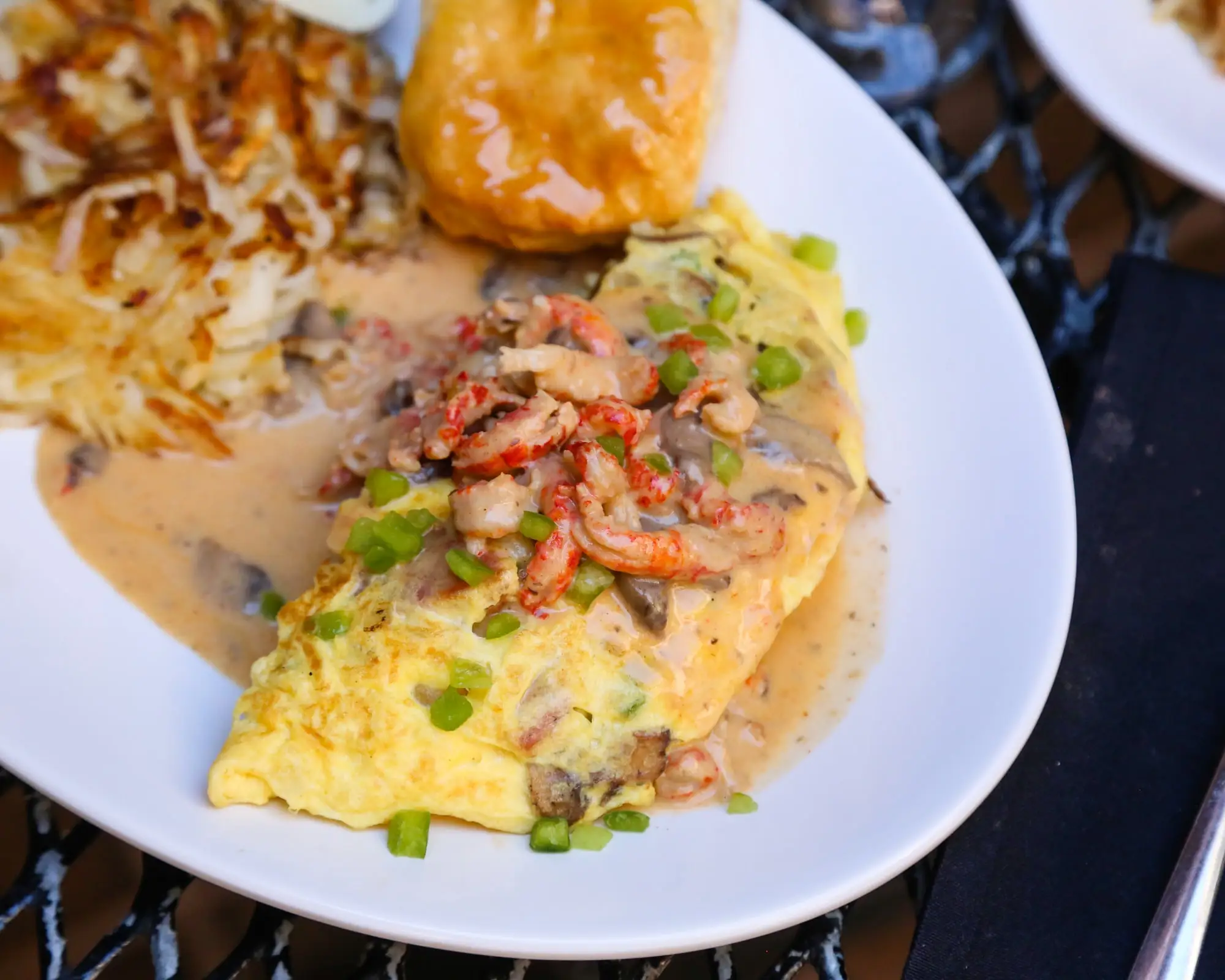 An omelette smothered in crawfish mushroom cream sauce, with hash browns and a biscuit