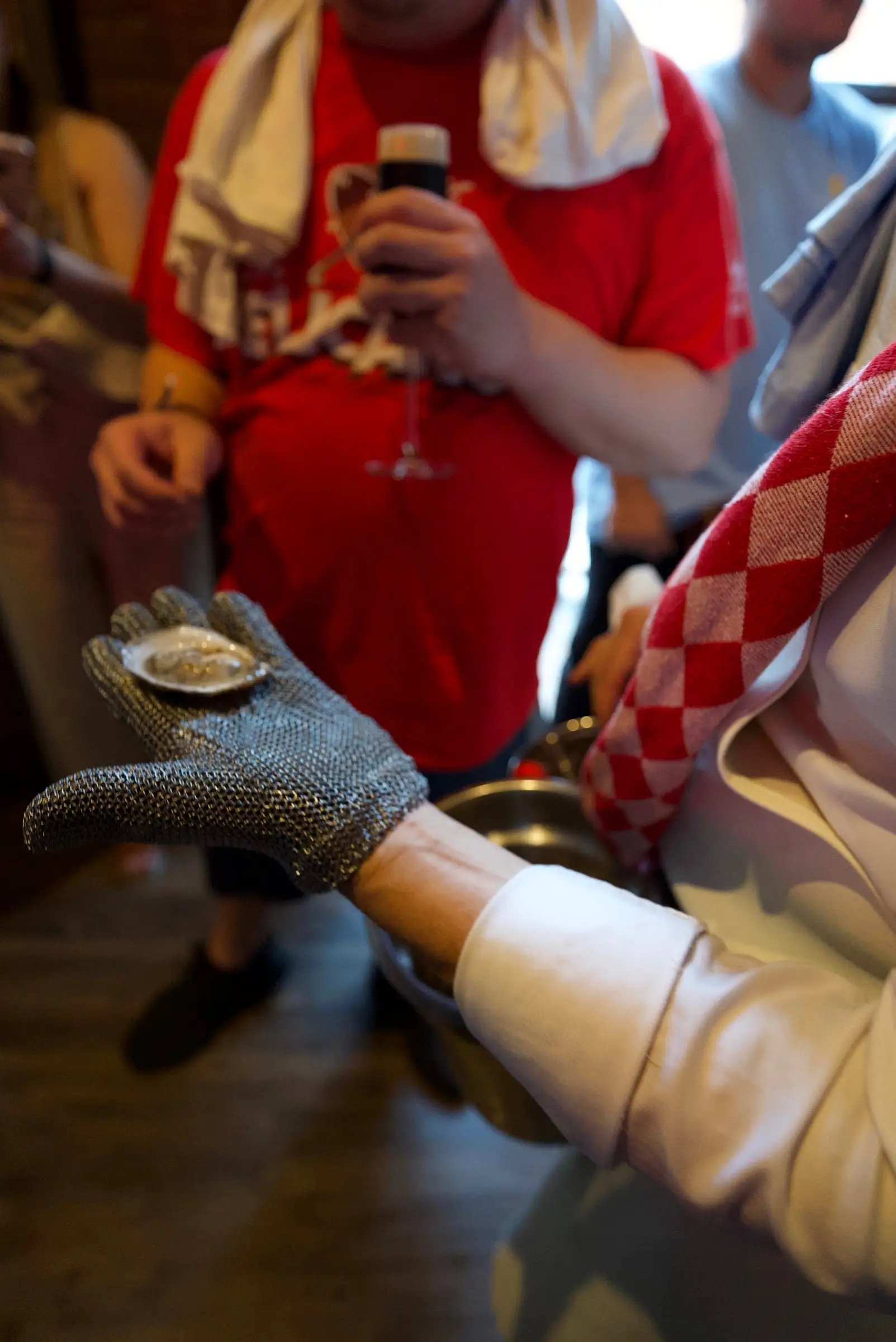 A gloved hand holding a freshly shucked oyster